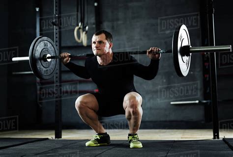 Active man lifting weight during workout in gym - Stock Photo - Dissolve