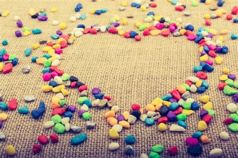 Colorful pebbles form a heart shape on canvas ground | Premium Photo