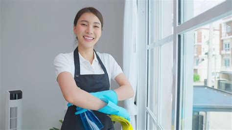 亚洲年轻清洁服务女工在房子工作的肖像。美丽的女孩主妇管家清洁工交叉手臂微笑，在做家务或家务后看着相机。视频素材_ID ...
