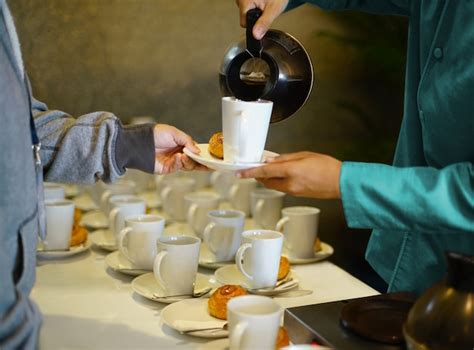 Waiter pouring hot coffee or tea into white cup and serve bakery dish ...