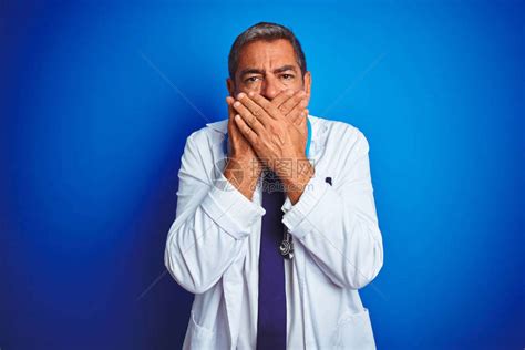穿着听诊器的中年帅男医生在孤立的蓝色背景上戴着耳光高清图片下载-正版图片504433612-摄图网