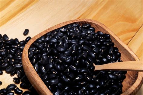 Premium Photo | Black soy beans in wooden scoop isolated on wood table ...