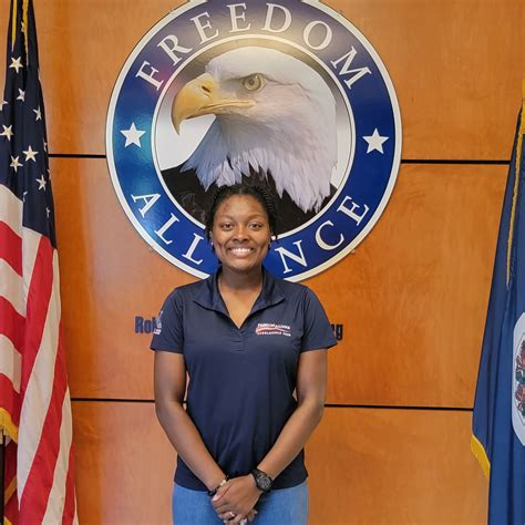 Kiki Patterson standing in front of a sign with the Freedom Alliance logo.