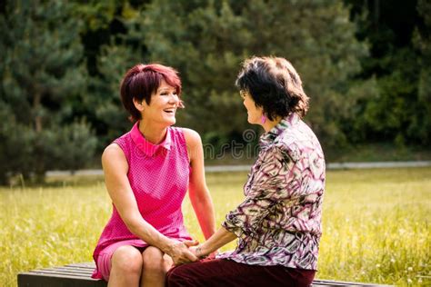 Adult daughter talking to her senior parents on a bench in a park