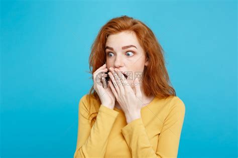 使用手机与朋友交谈时以令人震惊和紧张的表情描绘姜红头发女孩的肖像隔绝在蓝面纸背景上复制空间高清图片下载-正版图片303660409-摄图网