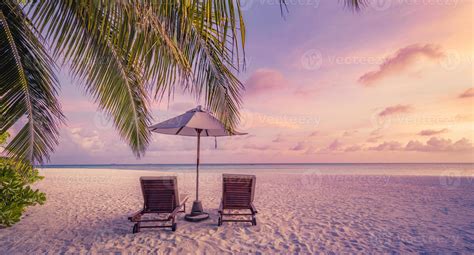 Beautiful tropical island sunset, couple sun beds chairs umbrella under ...