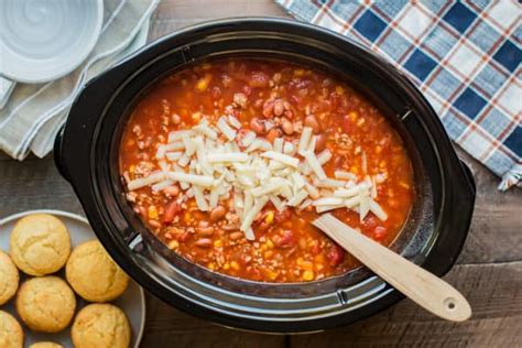 A bowl of Laura's quick slow cooker turkey chili, topped with shredded cheese, sliced green onions,