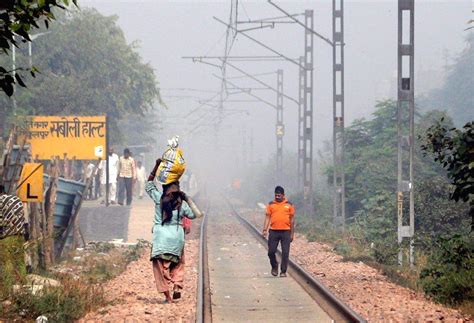 Pedestrians walk along railway tracks amid hazy conditions as smog ...