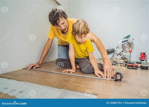 Father and Son Installing New Wooden Laminate Flooring on a Warm Film ...