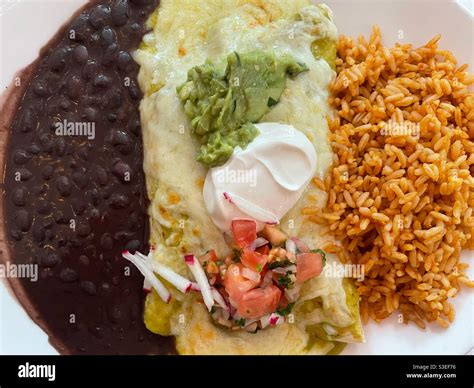 Flat lay of an enchilada meal with sides of yellow rice and black beans ...