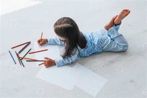 Lying on the floor and drawing. Cute little girl indoors at home alone 15301351 Stock Photo at ...