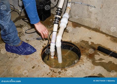 A Plumber Repairing a Sump Pump in a Flooded Basement in a Residential ...