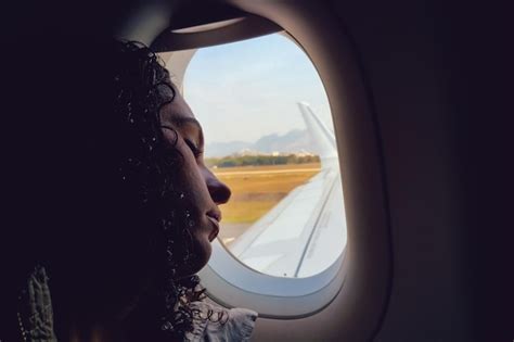 Young woman resting head on airplane window | Premium Photo