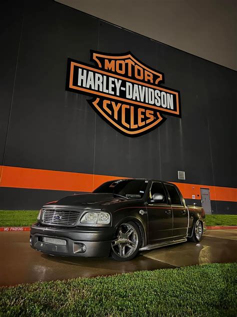 Black Car Parked in Front of Harley Davidson Cycles Sign
