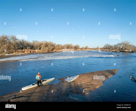 male paddler with a decked expedition canoe on a sandbar with ice floe ...