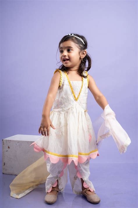 Charming white dhoti-style set with floral embroidery and playful yell ...