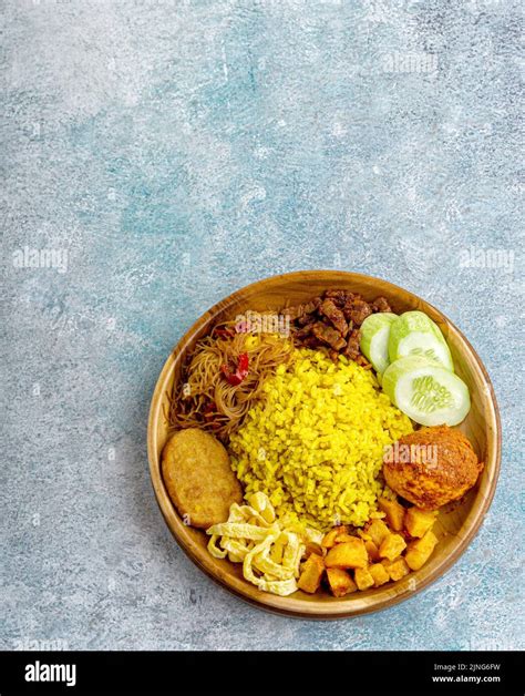Indonesian yellow rice served with egg, vermicelli, potato fried chili ...
