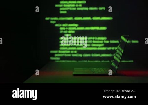 Laptop in dark room with glowing green programming code projected behind screen. Hacking, cybersecurity threats, cybercrime, and digital intrusion technology concept. Space for text Stock Video Footage - Alamy