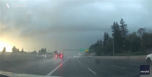 Frightening moment car swerves over several lanes, hits truck amid wet road conditions