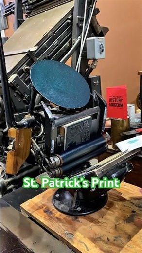 Printing a St. Patrick’s Day woodcut with green ink using a tabletop printing press