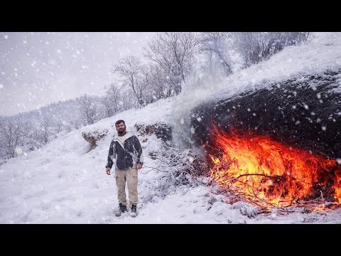 Fire Carving a Survival Shelter in Extreme Cold.Building Stone Shelter with Fireplace in rainstorm