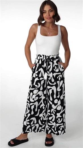 Elevate your everyday style with our Jaxie Pants - Black. Crafted from soft rayon, these boho-chic pants keep you cool and stylish even on hot days. Stand out with the retro graphic print. Perfect blend of comfort and statement-making fashion. SHOP HERE: saltycrush.com/products/jaxie-pants-black | Salty Crush