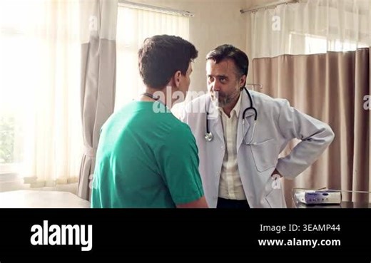 A doctor in a white coat advises a medical professional in scrubs during a consultation inside a bright clinic room Stock Video Footage - Alamy