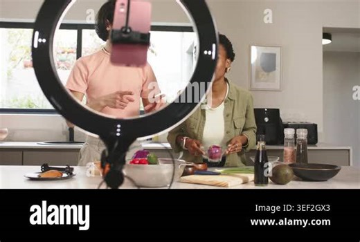 Diverse co-hosts initiating cooking tutorial by adjusting camera setup and slicing onion in kitchen. Cooking, collaboration, kitchen, lifestyle, vibrant, education, healthy Stock Video Footage - Alamy