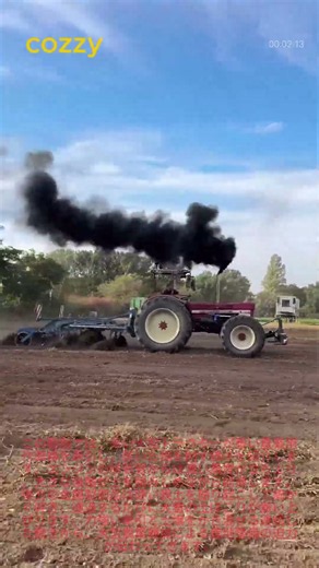 黒煙を上げながら乾いた畑を耕す大型トラクター：重い農機具で進む耕起作業 🚜