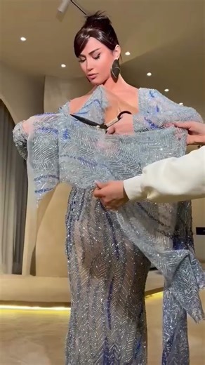 Share with a friend who would own the spotlight in this icy blue crystal corset column gown! To