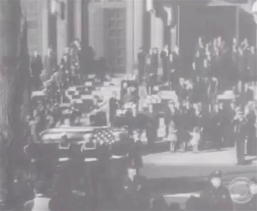 A pivotal moment in American history on November 25, 1963. It shows Jacqueline Kennedy with her children, Caroline and John F. Kennedy Jr., during the state funeral of President John F. Kennedy. The moment specifically depicts three-year-old John F. Kennedy Jr. saluting his father's passing casket. The scene took place outside St. Matthew's Cathedral in Washington, D.C., following the funeral mass. This poignant act became one of the most iconic and heartbreaking images of the 20th century. © Vi