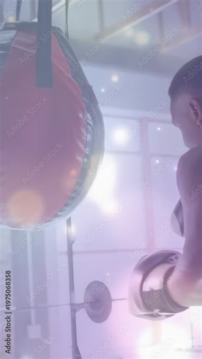 Vertical video: Male boxer shifting weight and landing jabs and hooks on red heavy bag, training