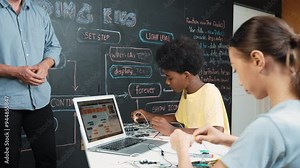 Teacher teaching about coding system while diverse academic student fixing main board at table with laptop display programming prompt or engineering code at STEM technology classroom. Edification