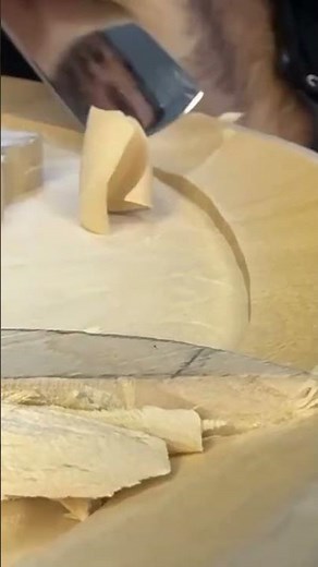 The process of scraping on a wood using a sharp tool by a craftsman