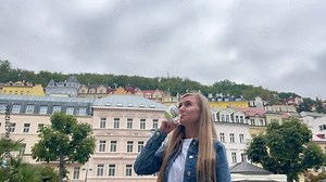 A young woman drinks a cup of healing mineral water at a natural hot spring in Karlovy Vary, Czech Republic.