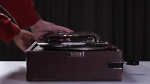 opening the lid of a portable vintage gramophone and starting the vinyl player. retro music concept