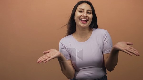 Young hispanic woman with open palms blowing a kiss in studio against peach backdrop wearing lilac top and jeans; playful affectionate joy Stock Video Footage - Alamy