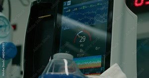 Close up on modern patient monitor show rhythm, SPO2, blood pressure, temperature, respiratory rate, blood pressure, blood oxygen saturation on screen. Real life surgery
