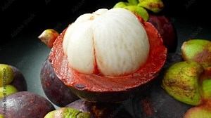 Behold the magnificence of a mangosteen, its robust purple rind embraces segments of pristine white flesh. This close-up exudes exotic allure and promises a tantalizing sensory experience.