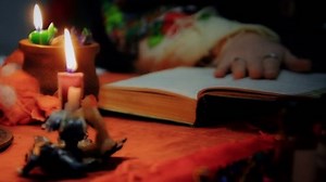 Female psychic invoking the spirits with burning candles, magic and wizards