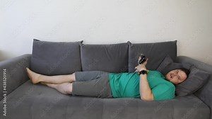 man playing video games eating croissant laying down on the coach