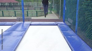 teenager boy demonstrates how to do a somersault on a trampoline