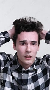Terrified man becomes nervous and scared, holds to the head on white background. Nightmare, shock and astonishment concept. Vertical video.