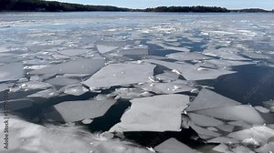 Winter video over a melting lake Mälaren or Malaren. Ice floating on the cold water. Swedish landscape. Sliding view. Peaceful and bright weather. Hässelby, Stockholm, Sweden, Scandinavia, Europe.