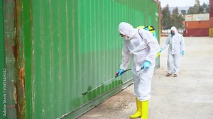 People wearing protective suits spray disinfectant chemicals on the cargo container to prevent the spreading of the coronavirus.
