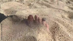 women's feet are buried in the river sand on the beach in summer