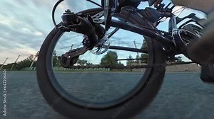 Cyclist rides mountain bicycle along paved country village rural road. Work of chain drive, rear derailleur with cassette. Gearshift. Jockey wheels, idler lower upper pulley. Cogset cogs. Shift gears