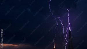 A dramatic sky filled with lightning strikes, alongside a tall power line tower.
