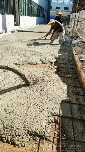 Concrete Pouring Site: Workers Using Tools to Level Freshly Poured Cement Slab