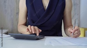 Businesswoman with blue dress is using dark calculator and taking notes in her office. Taxes and audit in business